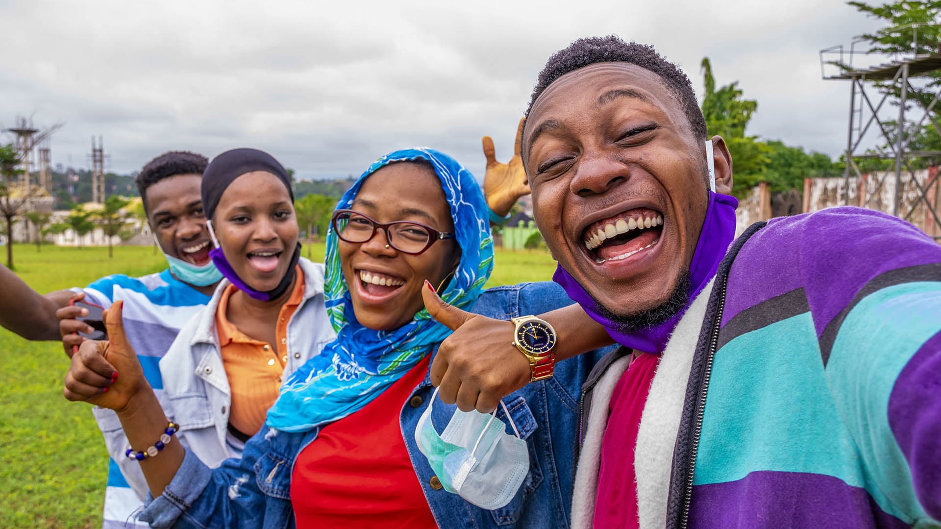 Friends taking a group selfie with thumbs up